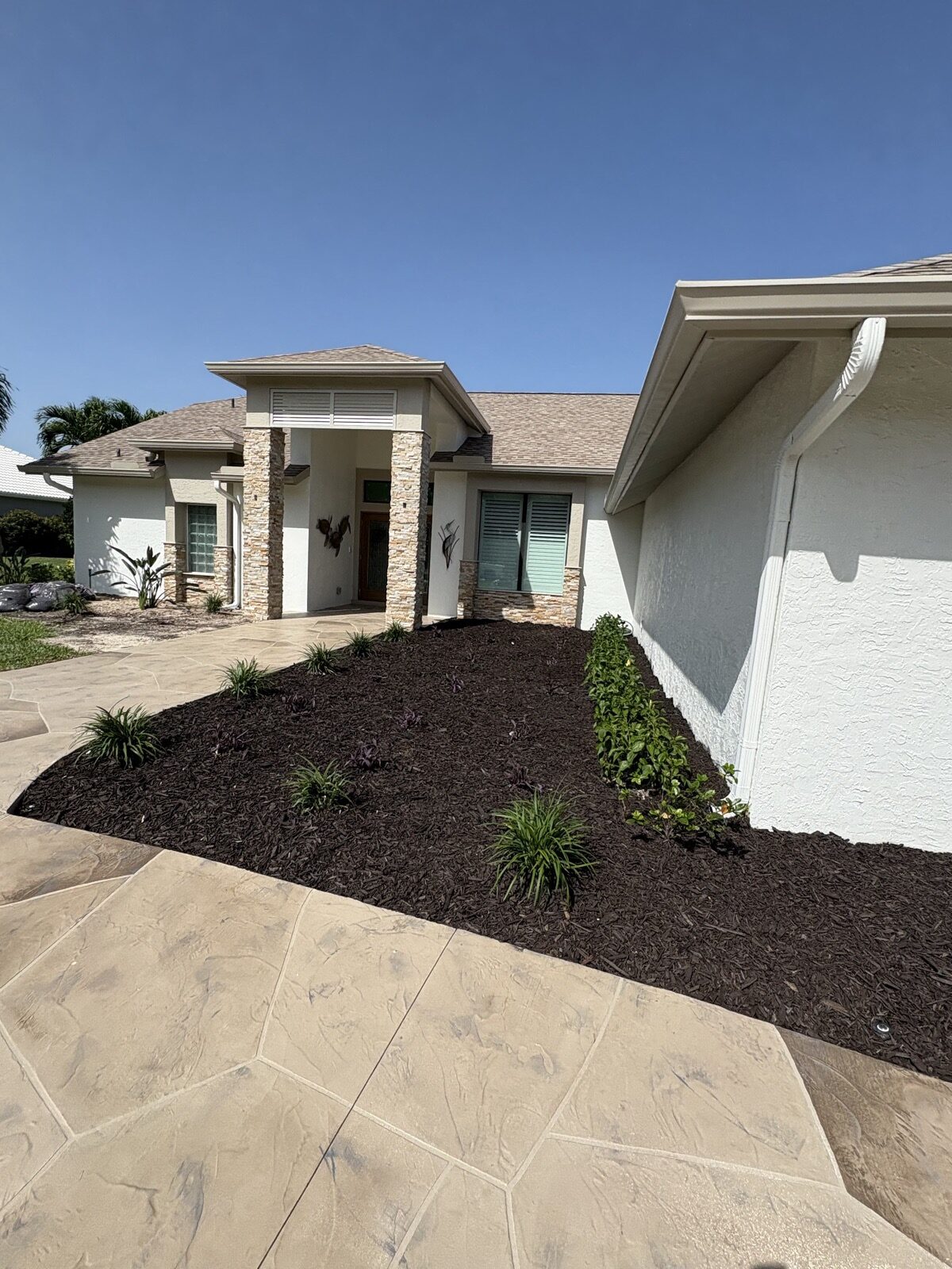 Fresh mulch bed at a stone-facade front entry in Cape Coral